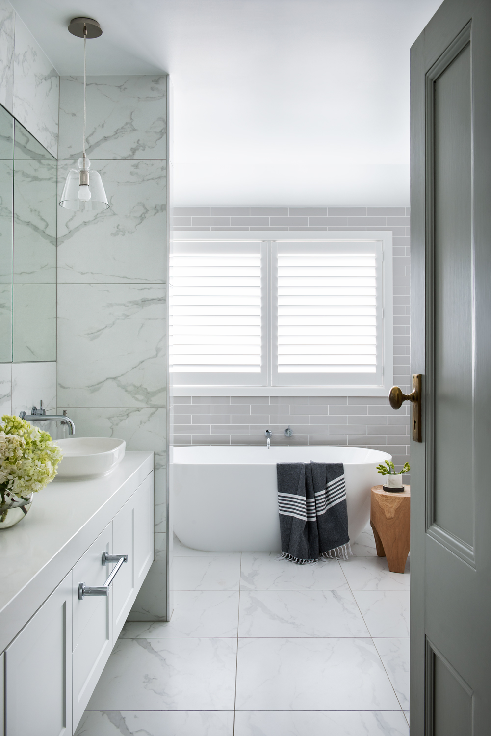 white marble bathroom design with grey tiling and white bathtub