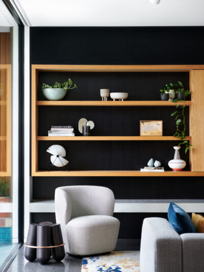 An open-plan lounge with open shelves made of natural timber.