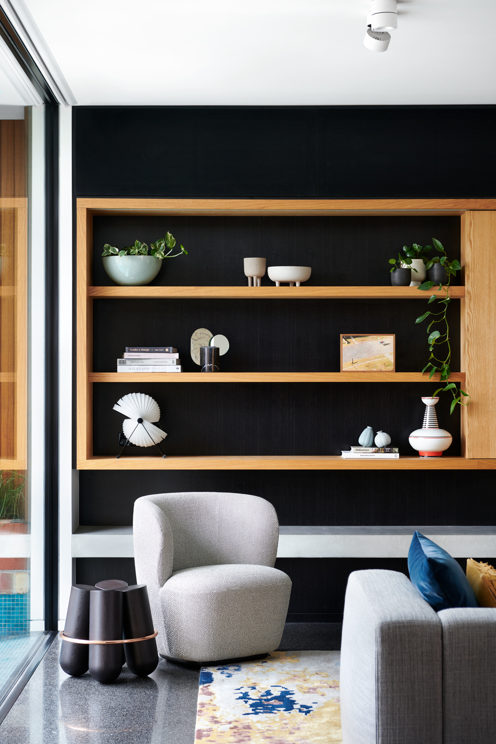 An open-plan lounge with open shelves made of natural timber.