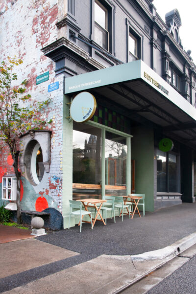Exterior view of Better Burnt café with green signage, outdoor seating, and heritage brick wall.