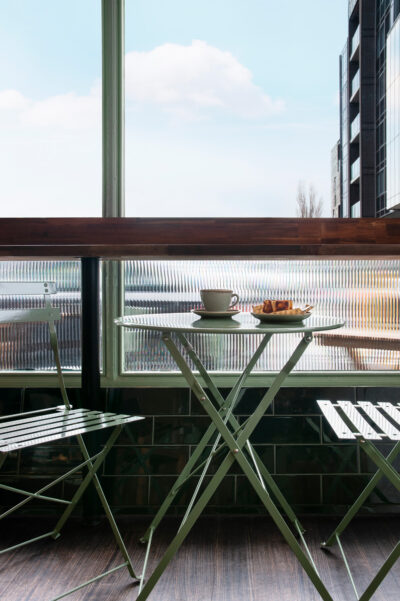 Green bistro chairs and table with coffee and Basque cheesecake inside Better Burnt café Hawthorn.