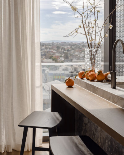 Kitchen bench with marble surface, modern sink, and decorative vase with branches in Collingwood apartment.