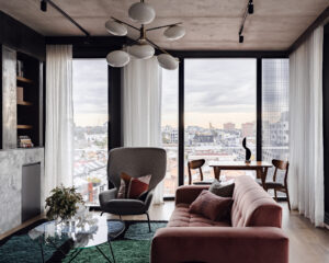 Open-plan living room with pink sofa, armchair, dining table, and city views in Collingwood apartment.