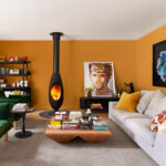 Colourful Australian living room with mustard walls, green velvet sofa, and modern fireplace.