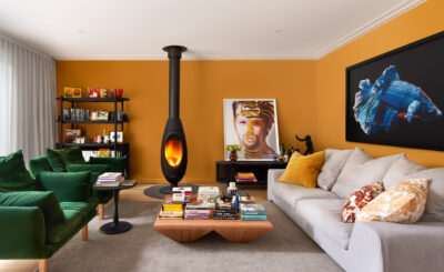 Colourful Australian living room with mustard walls, green velvet sofa, and modern fireplace.