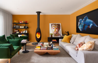 Colourful Australian living room with mustard walls, green velvet sofa, and modern fireplace.