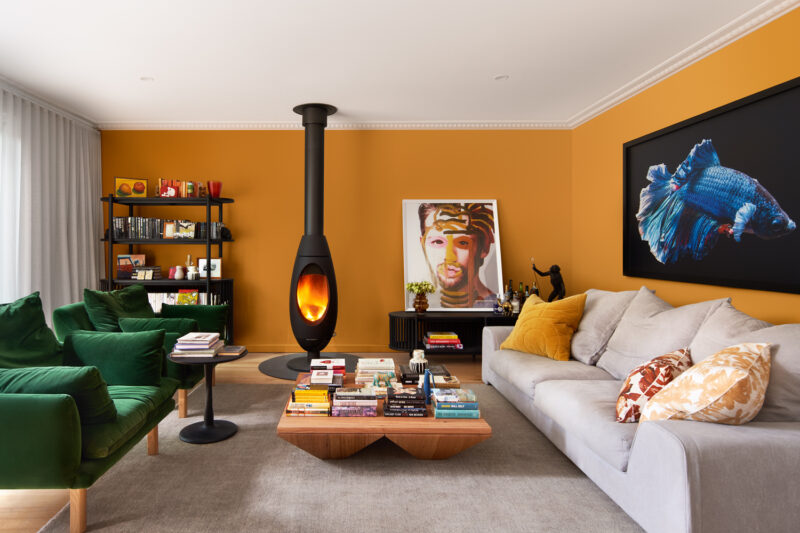 Colourful Australian living room with mustard walls, green velvet sofa, and modern fireplace.