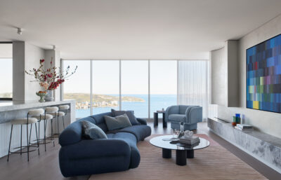 Modern Sydney living room with ocean views, blue curved sofa, and contemporary artwork.