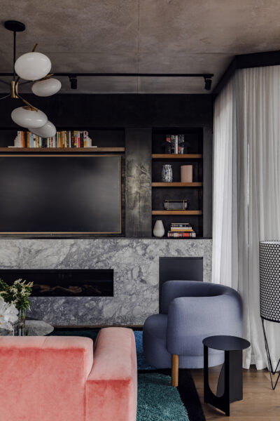 Living room with marble fireplace, black feature wall, and timber shelving in Collingwood apartment.