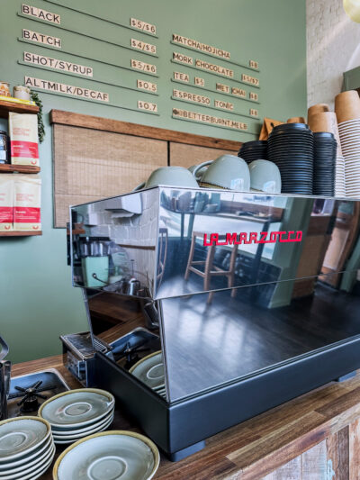 La Marzocco espresso machine on timber counter with sage green café menu wall at Better Burnt.