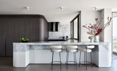 A Sydney kitchen styled with a striking marble island, fluted details, and sleek bar seating.