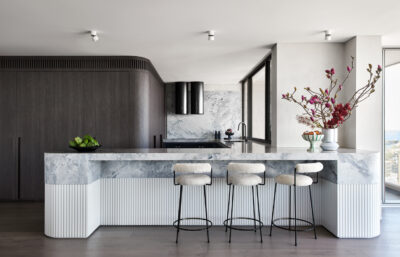 A Sydney kitchen styled with a striking marble island, fluted details, and sleek bar seating.