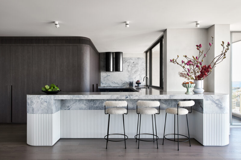 A Sydney kitchen styled with a striking marble island, fluted details, and sleek bar seating.