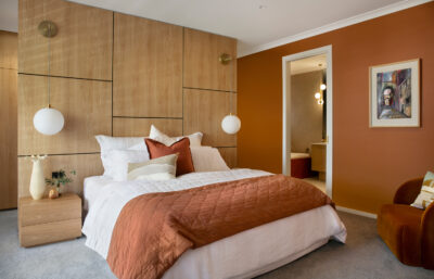 Warm bedroom with timber panelling and terracotta tones, styled with pendant lighting.