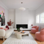 Living room with boucle sofa, pink armchairs, and modern artwork.
