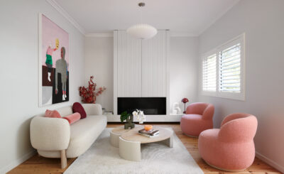 Living room with boucle sofa, pink armchairs, and modern artwork.