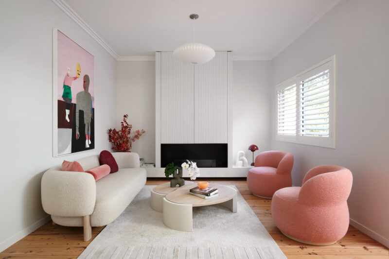 Living room with boucle sofa, pink armchairs, and modern artwork.