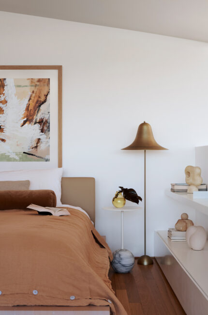 Contemporary bedroom with neutral tones, art, and sculptural lamp designed by The Stylesmiths.