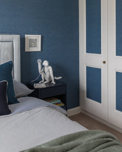 Blue bedroom with panelled wardrobe doors and striped headboard.