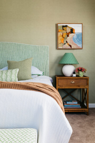 Bedroom with timber bedside table, green headboard, and soft neutral bedding.