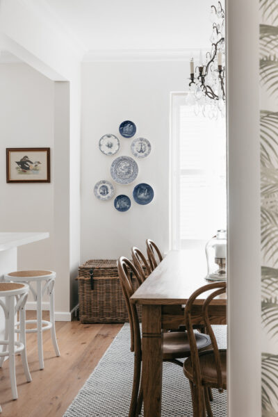 Dining area with wall-mounted blue and white plates and timber furniture.