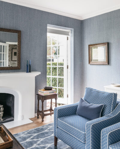 Elegant blue living room with white fireplace and patterned rug in a Toorak heritage home.
