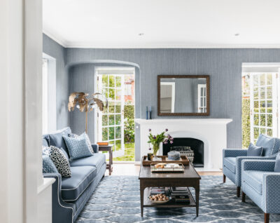 Elegant blue living room with white fireplace and patterned rug in a Toorak heritage home.