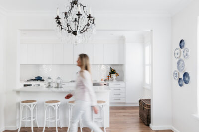 Blue and white wall plates in a white kitchen with rattan storage basket and timber floors.