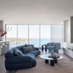 Contemporary coastal living room with ocean views, blue sofa, and modern artwork.