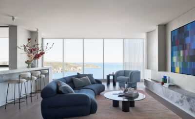 Contemporary coastal living room with ocean views, blue sofa, and modern artwork.
