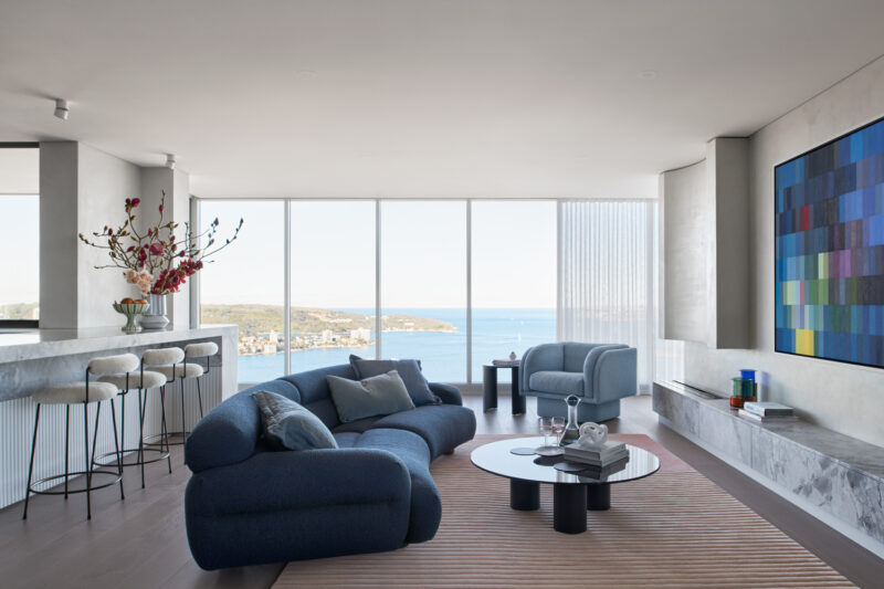 Contemporary coastal living room with ocean views, blue sofa, and modern artwork.