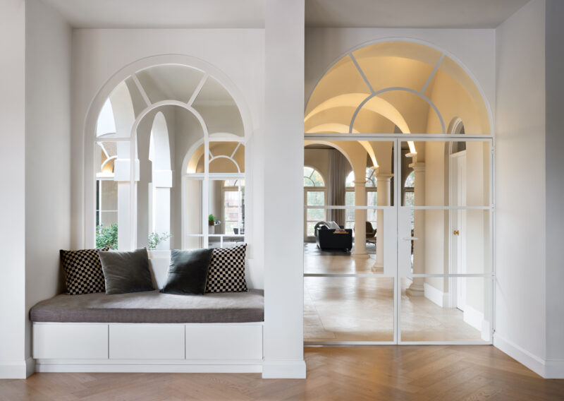 Heritage home interior with arched windows, white walls, and architectural detailing.