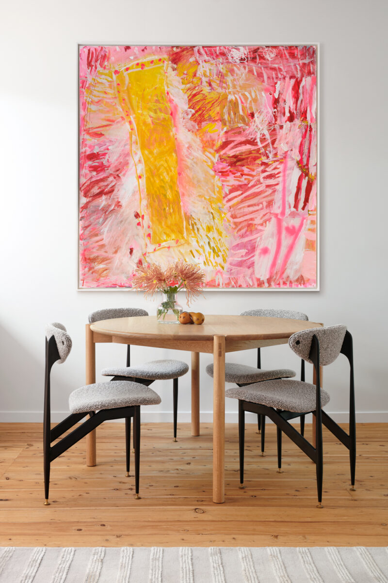 Dining room with timber table, sculptural chairs, and vibrant pink abstract artwork.