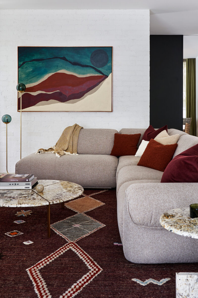 Modern dining room with timber table, sculptural chairs, and large colourful artwork.