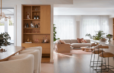 Scandinavian open-plan living and kitchen with warm timber cabinetry, soft pink accents and minimalist styling in Richmond by The Stylesmiths.