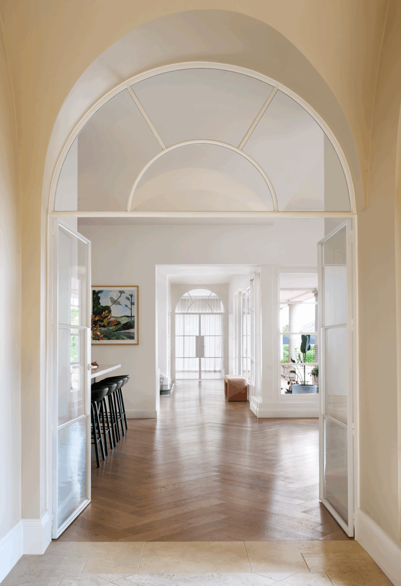 Hamptons style arched hallway in a Melbourne home by The Stylesmiths featuring classic detailing and light-filled interiors
