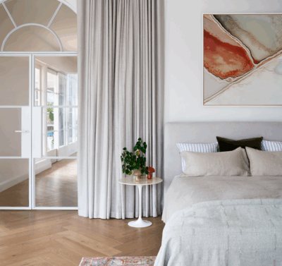 Hamptons bedroom interior in Melbourne by The Stylesmiths with soft neutral tones, layered textures and elegant drapery