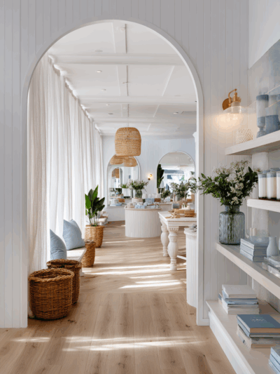 Hamptons-style retail interior in Brisbane featuring arched detailing, white timber finishes and coastal tonality by The Stylesmiths.