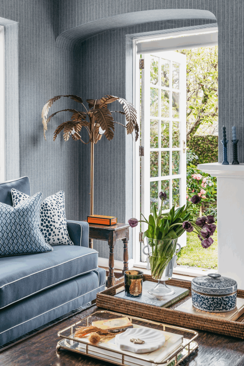 Hamptons sitting room in Brisbane with soft blue furnishings, classic detailing and garden connection by The Stylesmiths.